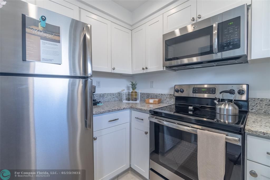 6520 North Ocean Boulevard, Unit 22 Boynton Beach, FL 33435 - Photo 5 of 27 a kitchen with stainless steel appliances granite countertop a refrigerator stove top oven a sink and dishwasher
