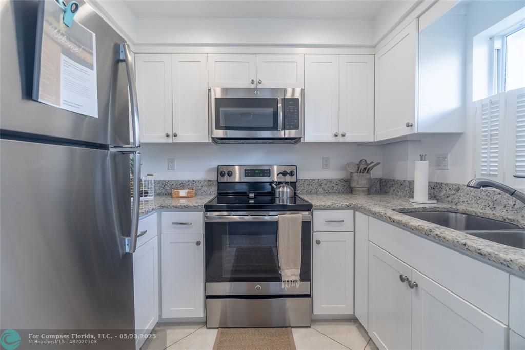6520 North Ocean Boulevard, Unit 22 Boynton Beach, FL 33435 - Photo 7 of 27 a kitchen with white cabinets and stainless steel appliances