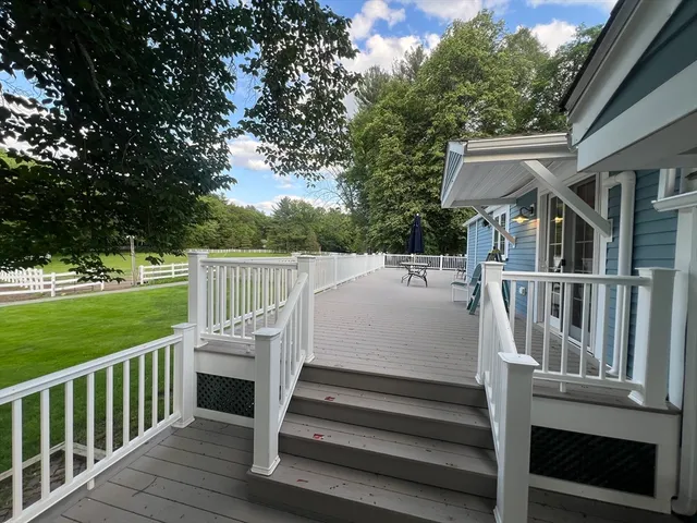 a view of a white house with a small yard and wooden fence