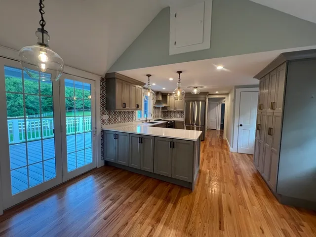 a large kitchen with stainless steel appliances granite countertop a large counter top a sink and a refrigerator