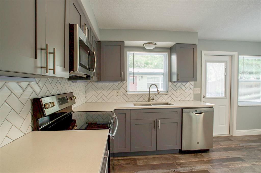 715 Bay Street Dunedin, FL 34698 - Photo 5 of 19 a kitchen with stainless steel appliances granite countertop a sink stove and cabinets