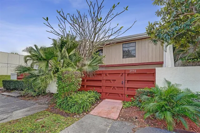 a view of a house with a small yard plants and large tree