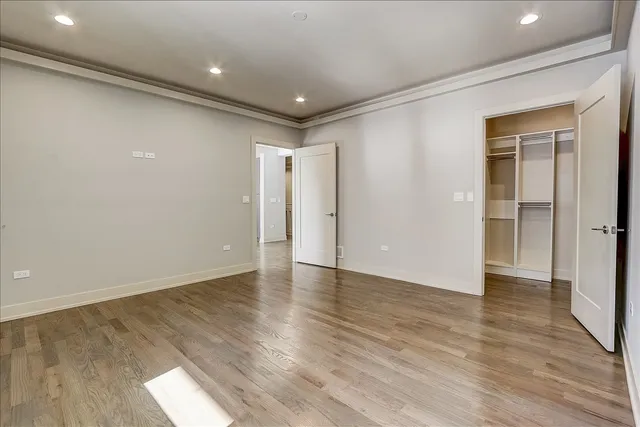 a view of an empty room with wooden floor and closet