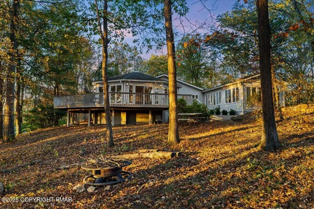 a view of a house with a small yard and large trees