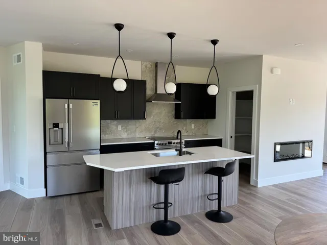 a kitchen with stainless steel appliances granite countertop a sink a microwave a refrigerator and a wooden floor