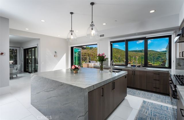 a kitchen with stainless steel appliances granite countertop a sink a stove and a kitchen island