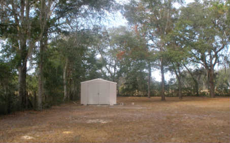 87073 Raddin Road Yulee, FL 32097 - Photo 18 of 20 a backyard of a house with trees and garage