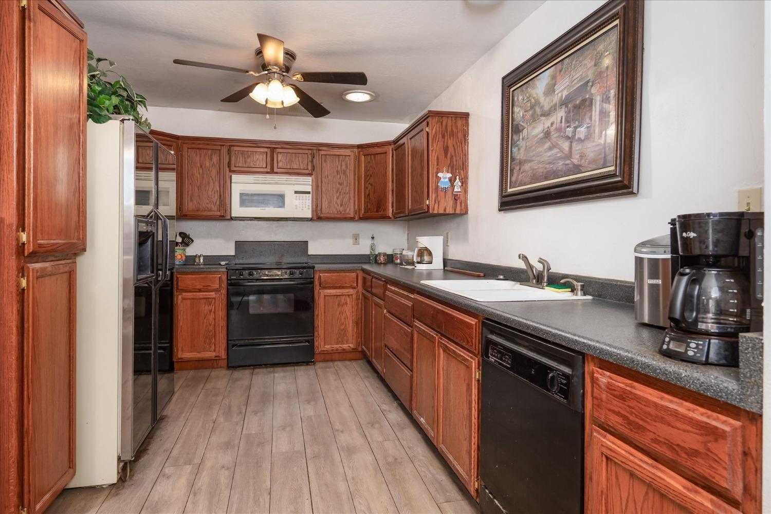 48994 Manzanita Road Oakhurst, CA 93644 - Photo 13 of 43 a kitchen with stainless steel appliances granite countertop a stove a sink dishwasher and a refrigerator with wooden floor