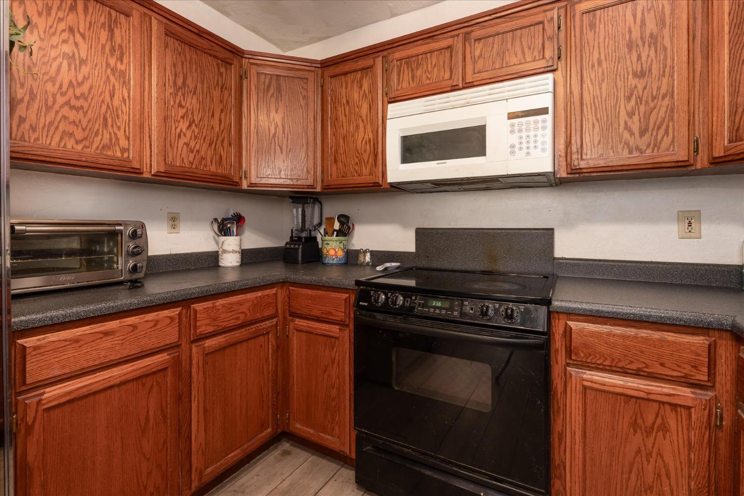 48994 Manzanita Road Oakhurst, CA 93644 - Photo 15 of 43 a kitchen with stainless steel appliances granite countertop wooden cabinets and a stove top oven