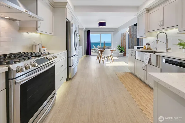 a kitchen with stainless steel appliances granite countertop a stove top oven a sink dishwasher a dining table and chairs with wooden floor