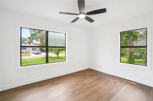 a view of an empty room with a window and wooden floor