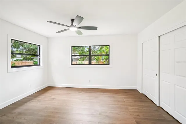 a view of empty room with wooden floor and fan