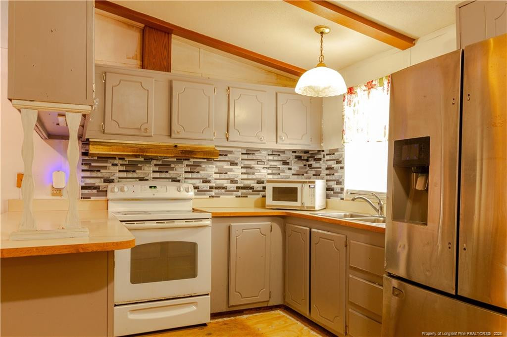 231 Knight Lane Autryville, NC 28318 - Photo 18 of 27 a kitchen with stainless steel appliances granite countertop a refrigerator a sink dishwasher and white cabinets with wooden floor