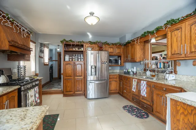a kitchen with stainless steel appliances granite countertop a refrigerator a stove and a sink