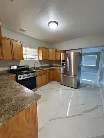 a kitchen with stainless steel appliances granite countertop a stove a sink and a refrigerator