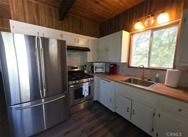 a kitchen with granite countertop stainless steel appliances a refrigerator sink and window