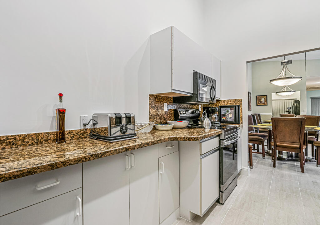 5121 Nesting Way, Unit D Delray Beach, FL 33484 - Photo 19 of 34 a kitchen with stainless steel appliances granite countertop a sink and a refrigerator