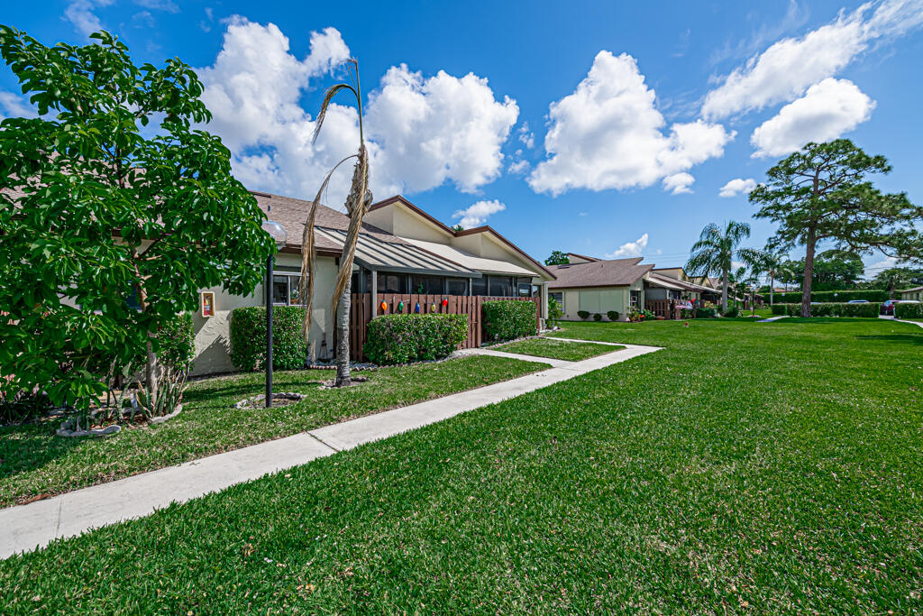 5121 Nesting Way, Unit D Delray Beach, FL 33484 - Photo 2 of 34 a view of a house with a big yard and a large tree