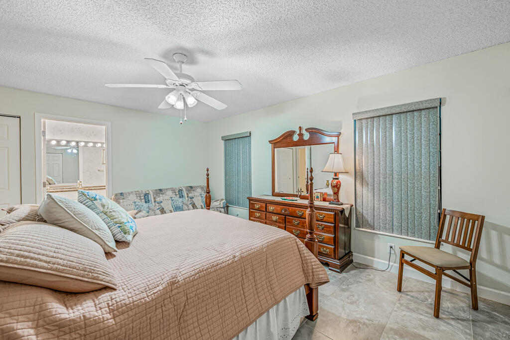 5121 Nesting Way, Unit D Delray Beach, FL 33484 - Photo 22 of 34 a bedroom with a bed and a chair with the wooden floor