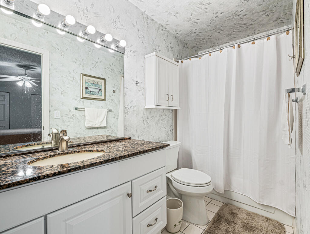 5121 Nesting Way, Unit D Delray Beach, FL 33484 - Photo 23 of 34 a bathroom with a granite countertop sink a toilet and a mirror