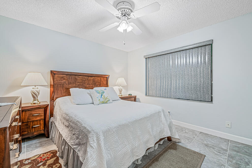 5121 Nesting Way, Unit D Delray Beach, FL 33484 - Photo 24 of 34 a bedroom with a bed and a chandelier