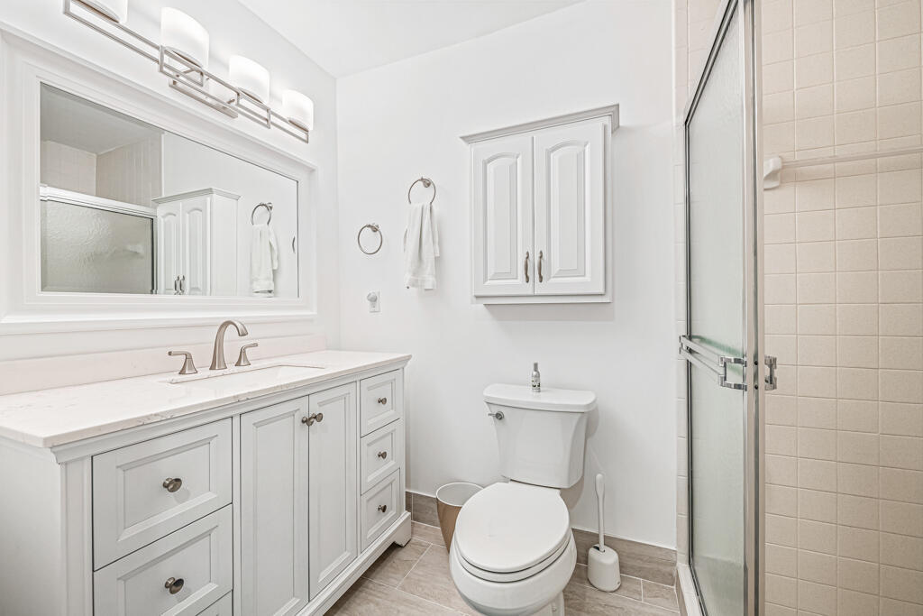 5121 Nesting Way, Unit D Delray Beach, FL 33484 - Photo 27 of 34 a bathroom with a toilet a sink a mirror and vanity