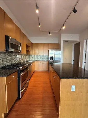 a large kitchen with stainless steel appliances kitchen island granite countertop a large counter top and a stove