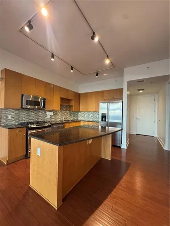 a kitchen with stainless steel appliances kitchen island granite countertop a stove and a sink