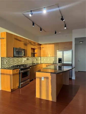 a large kitchen with stainless steel appliances kitchen island granite countertop a stove and cabinets