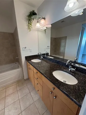 a bathroom with a granite countertop sink a mirror and a bathtub