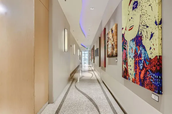 a hallway with painting on the wall and a large window