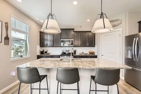a kitchen with granite countertop a counter space chairs stainless steel appliances and cabinets