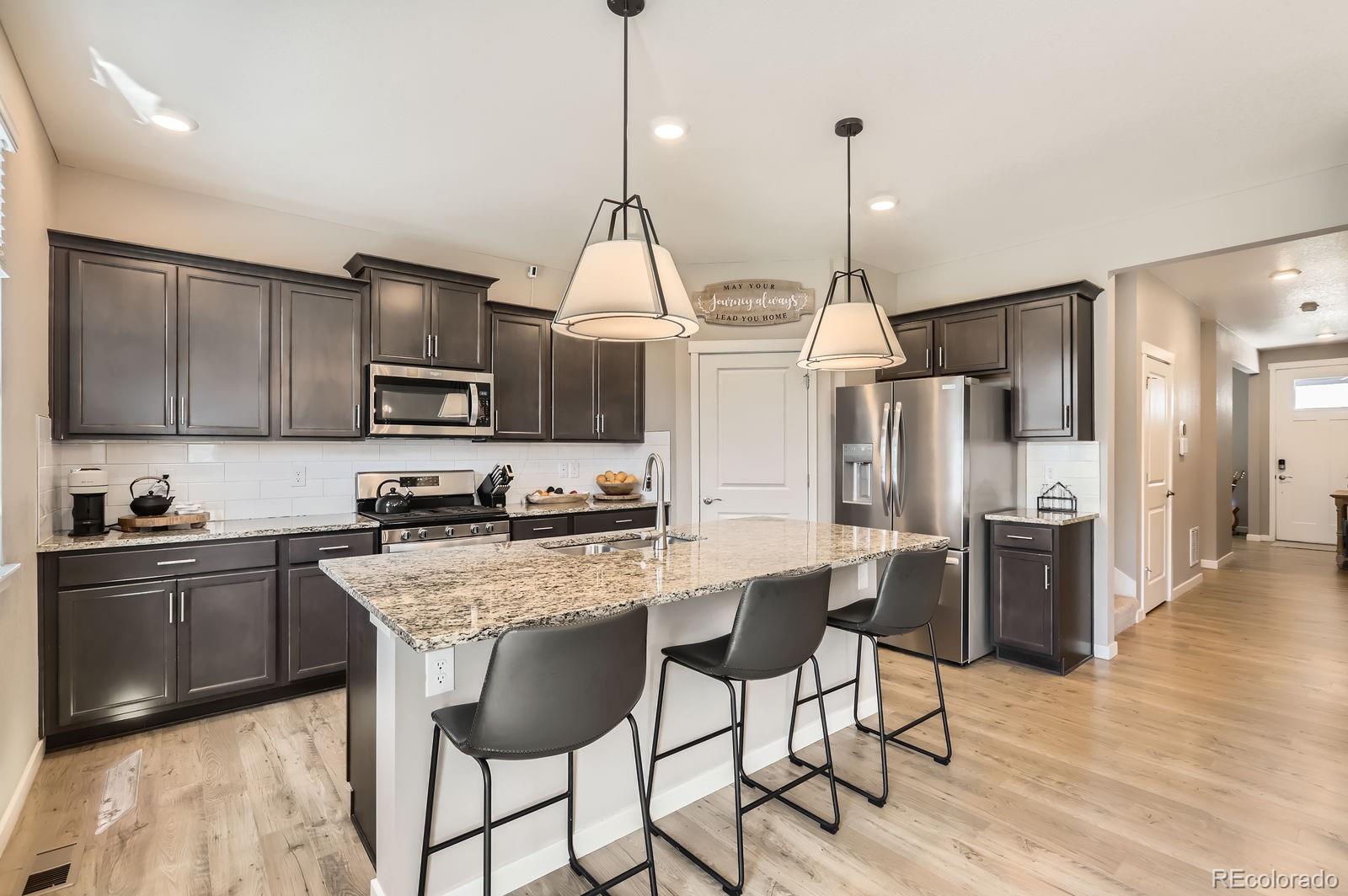 1591 Sun River Road Berthoud, CO 80513 - Photo 12 of 34 a kitchen with stainless steel appliances kitchen island granite countertop a sink a stove a refrigerator and island with wooden floor