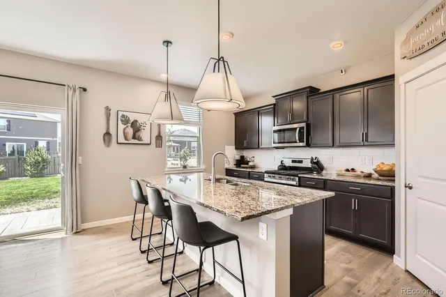 a kitchen with granite countertop a stove a sink dishwasher a refrigerator with wooden floor