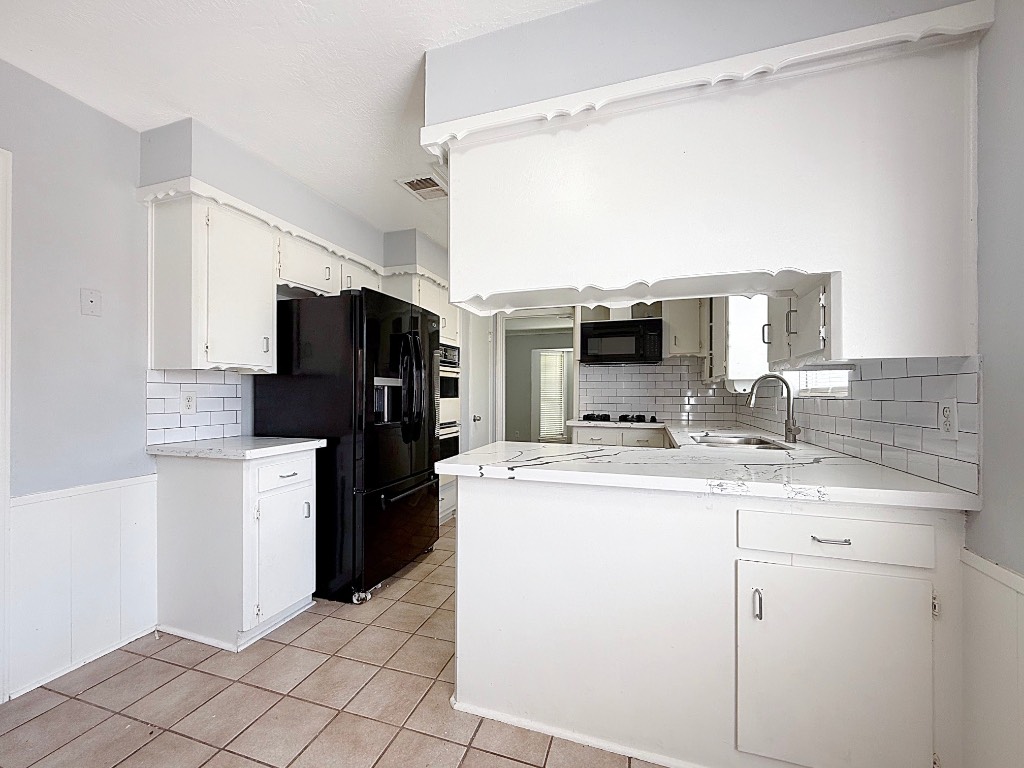 9206 Sharpview Drive Houston, TX 77036 - Photo 14 of 27 a kitchen with a sink a microwave a refrigerator and cabinets