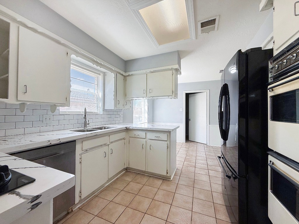 9206 Sharpview Drive Houston, TX 77036 - Photo 10 of 27 a kitchen with a sink a refrigerator and cabinets