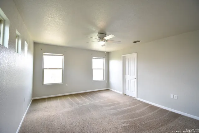 an empty room with windows and ceiling fan