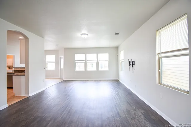 a view of an empty room with a window and wooden floor