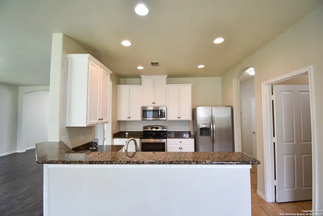 a kitchen with stainless steel appliances granite countertop a sink a refrigerator and a granite counter tops
