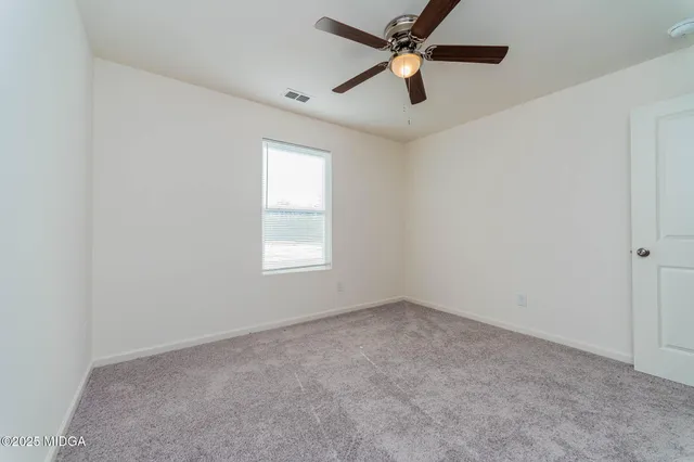 an empty room with a window and a fan