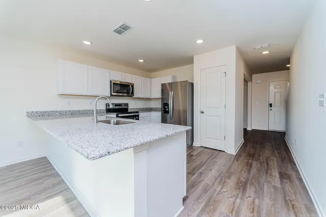 a kitchen with granite countertop a refrigerator stove and wooden floor