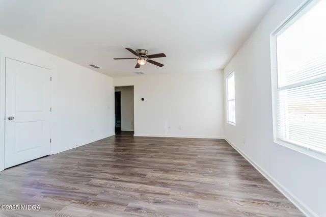 a view of an empty room with a window and wooden floor