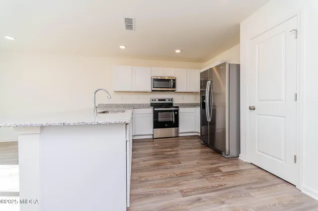 a kitchen with stainless steel appliances granite countertop a refrigerator and a stove top oven