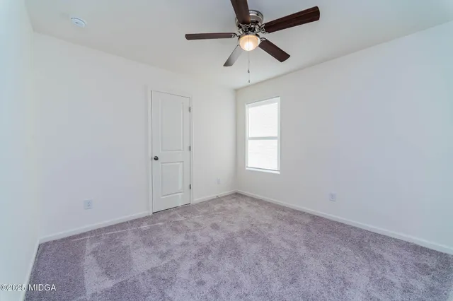 an empty room with a window and a fan