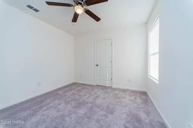 an empty room with a window and a fan