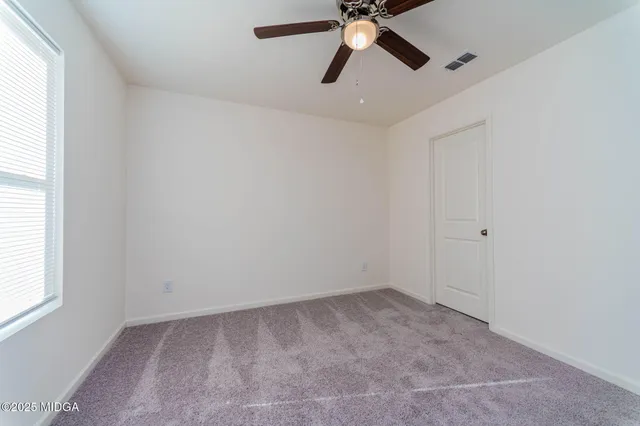 an empty room with a window and a fan