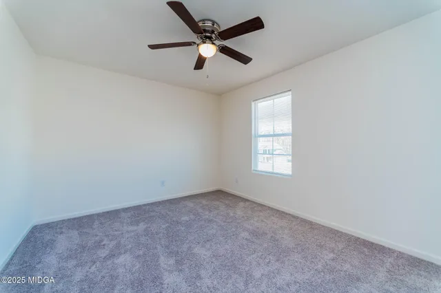 an empty room with a window and a fan