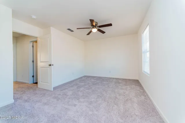 an empty room with a ceiling fan and a window