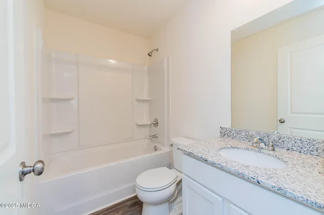 a bathroom with a granite countertop sink a toilet and a bathtub
