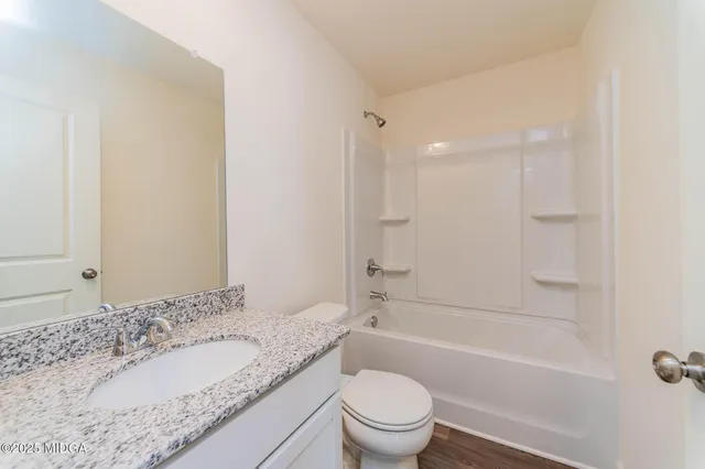 a bathroom with a granite countertop sink a toilet and bathtub